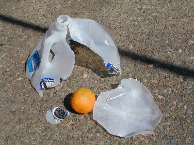 Milk jug full of water hit with an orange.