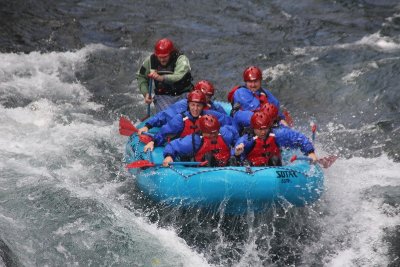 7 guys in a raft floating down the river.