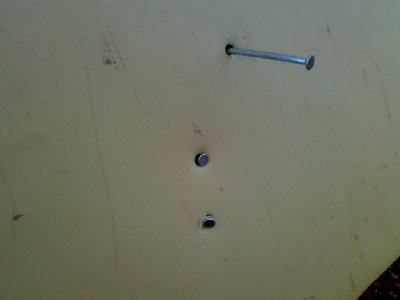 front view of nail puncture through two aluminium signs