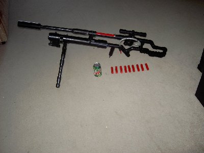 A comparisson of the size of the ammo and rifle next to a soda can.